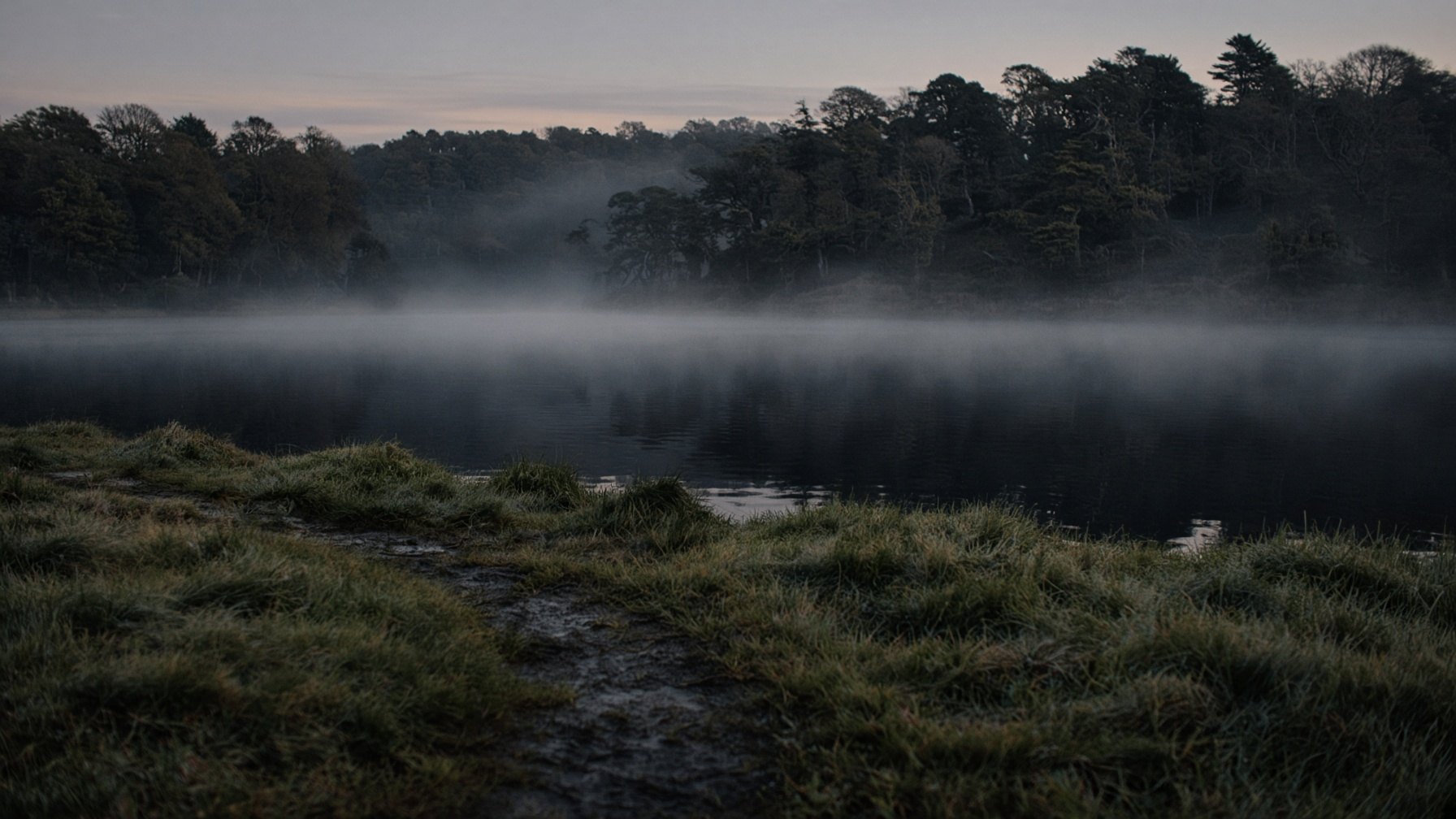 Mist over a still Cornish lake at first light